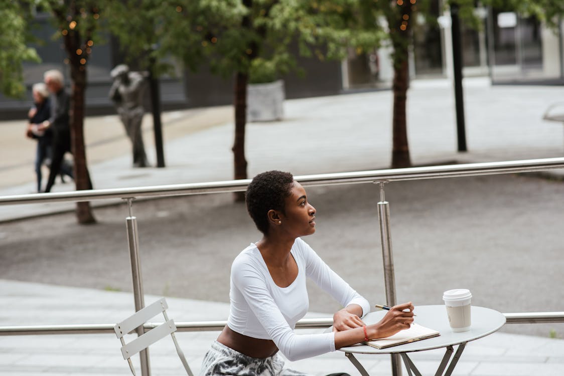 Pensive black woman with coffee and notebook