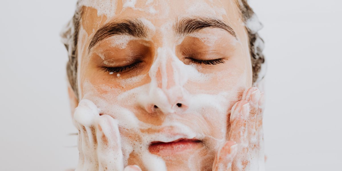 Woman washing her face with foam cleanser