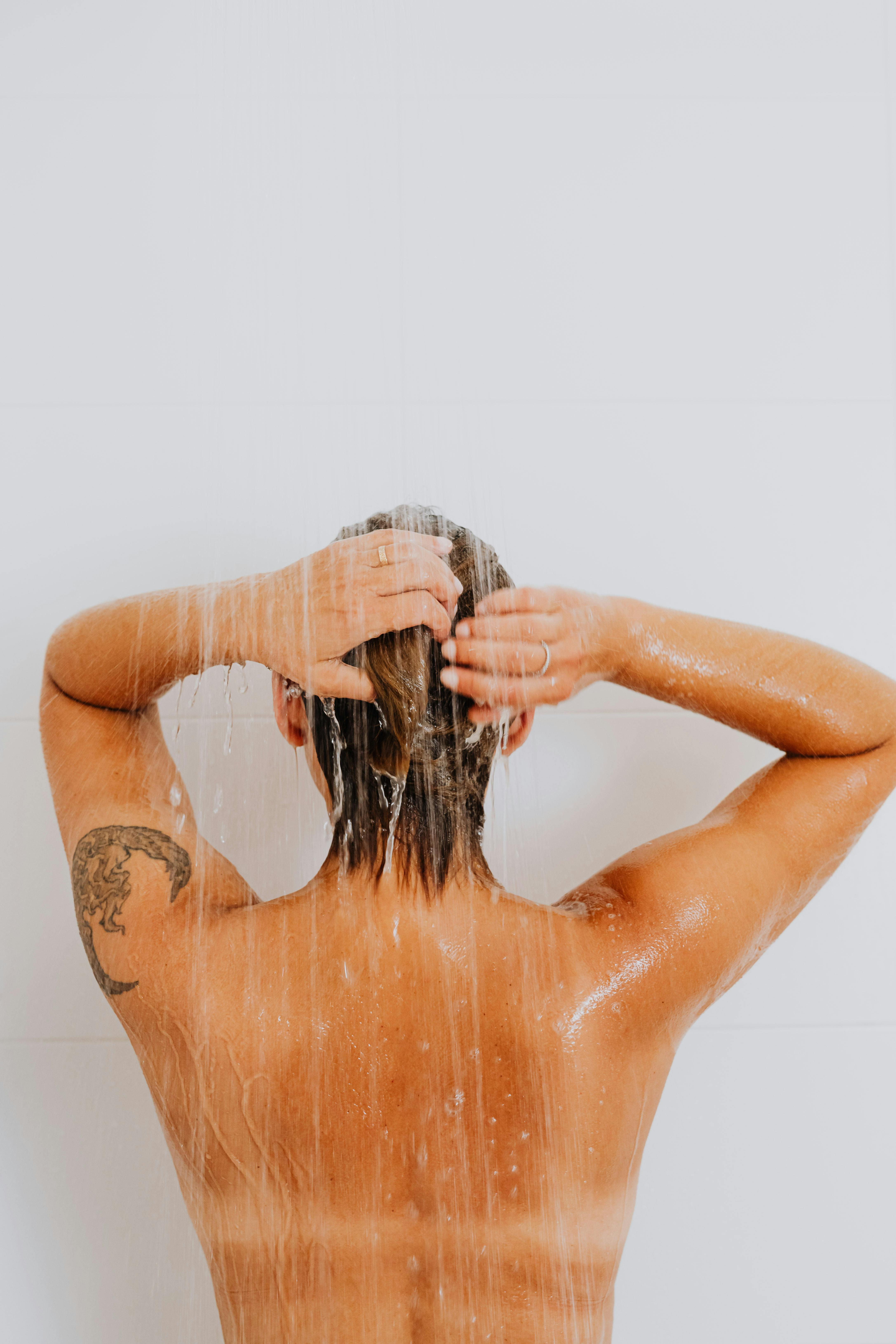a person with arm tattoo taking a shower