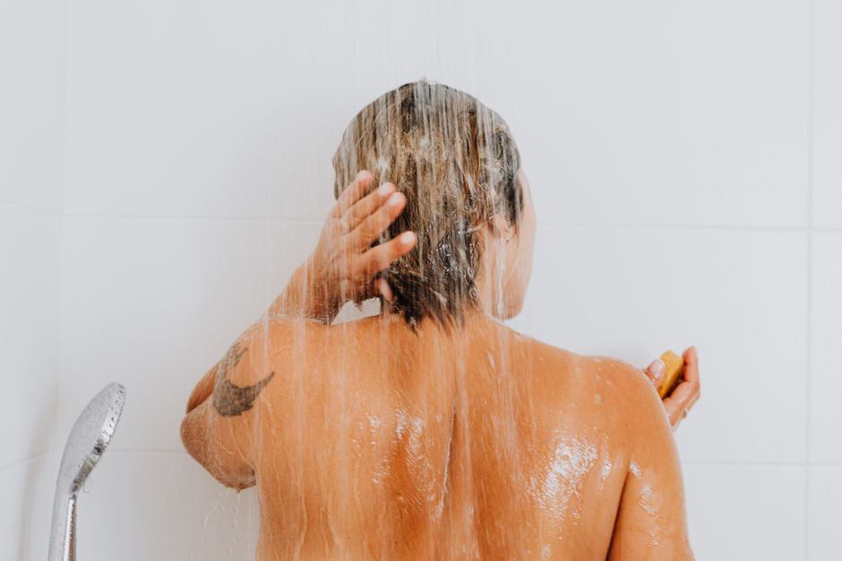 A person washing a new forearm tattoo gently with mild, unscented soap and lukewarm water