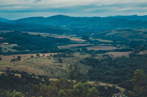 Free A stunning view of rolling hills and lush green valleys under a cloudy sky, offering a tranquil scenic landscape. Stock Photo