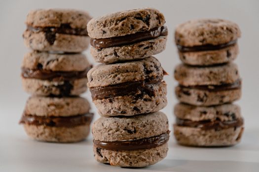 Close-up view of chocolate-filled cookies stacked on white background, showcasing delicious texture and filling.