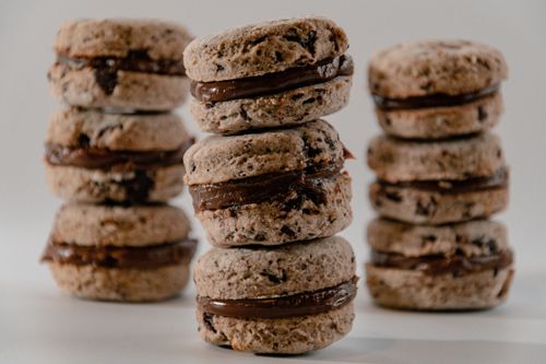 Free Close-up view of chocolate-filled cookies stacked on white background, showcasing delicious texture and filling. Stock Photo