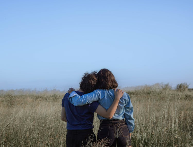 Anonymous Female Friends Embracing On Spacious Meadow