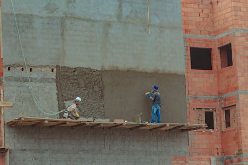 Construction site with builders on brick wall