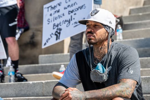 Pensive young black guy resting on street steps during anti racism protest