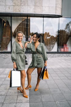 Two women in matching outfits happily shopping outdoors with multiple bags.