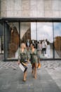 两名身穿时尚服装的女子拎着购物袋，一起在户外散步