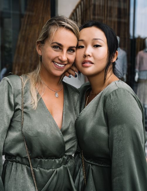 Two women in matching outfits pose happily outdoors, exuding warmth and friendship.