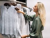 女人微笑着审视现代衣柜中优雅的服装选择