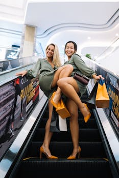 Two happy women enjoying a fun shopping day together riding on an escalator with shopping bags.