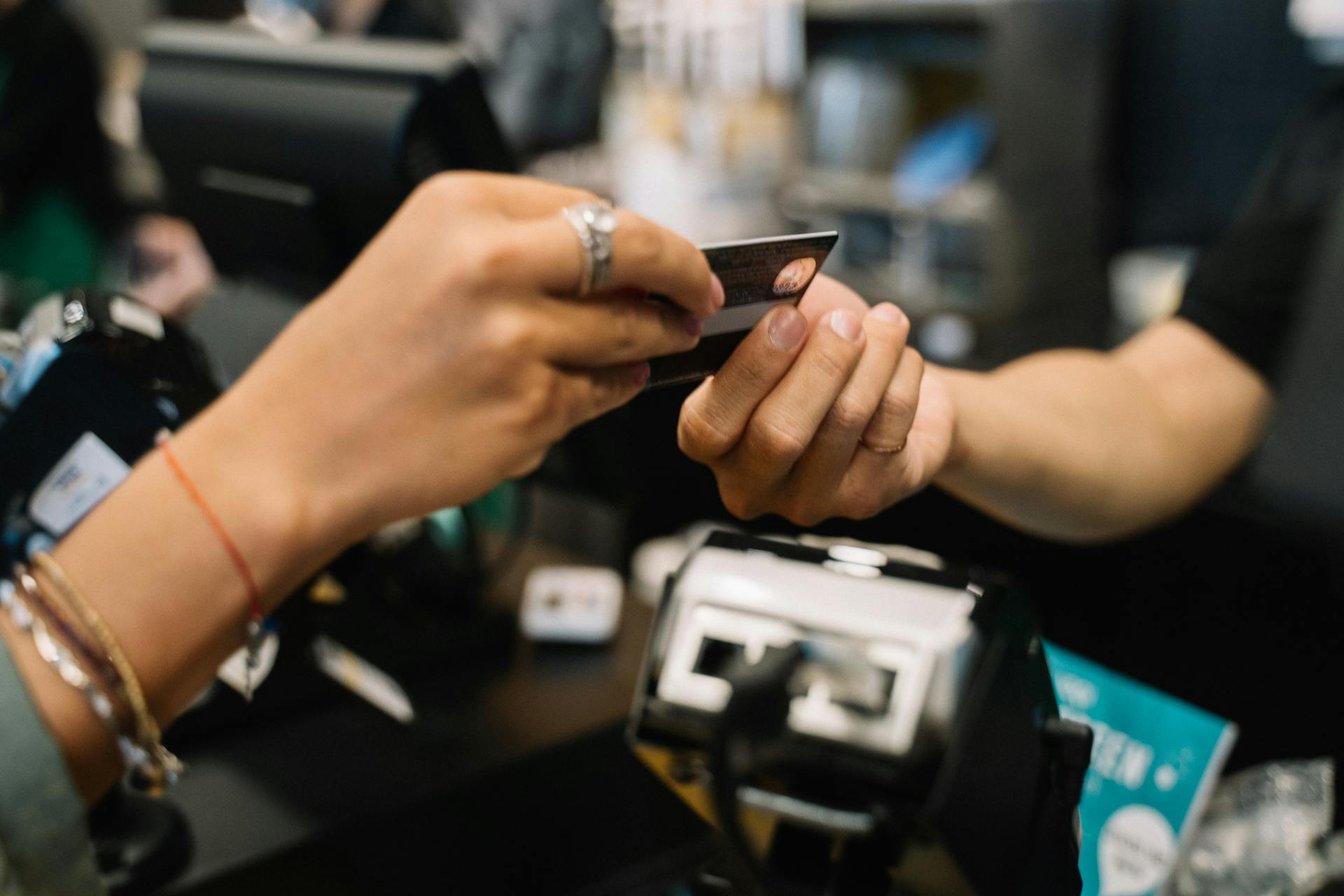 Close-up of hands completing a payment transaction at a retail checkout using a bank card.