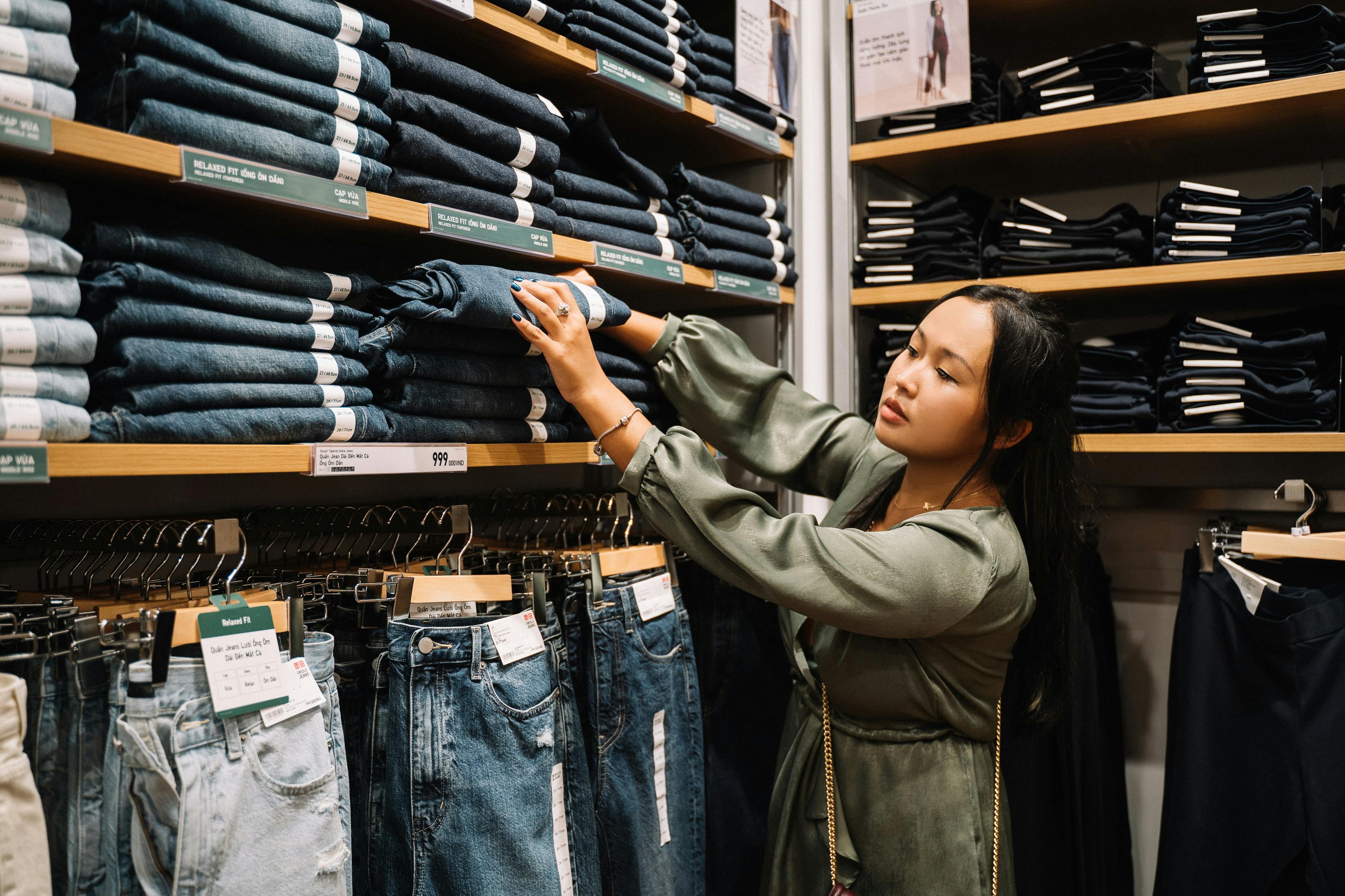 woman looking at the jeans on a wooden shelf