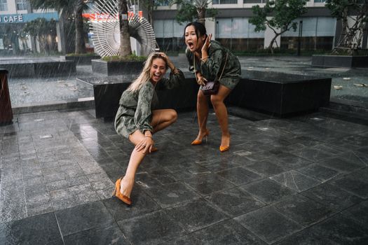 两名女子在城市广场上快乐地拥抱突然的阵雨，欢笑着，玩得很开心