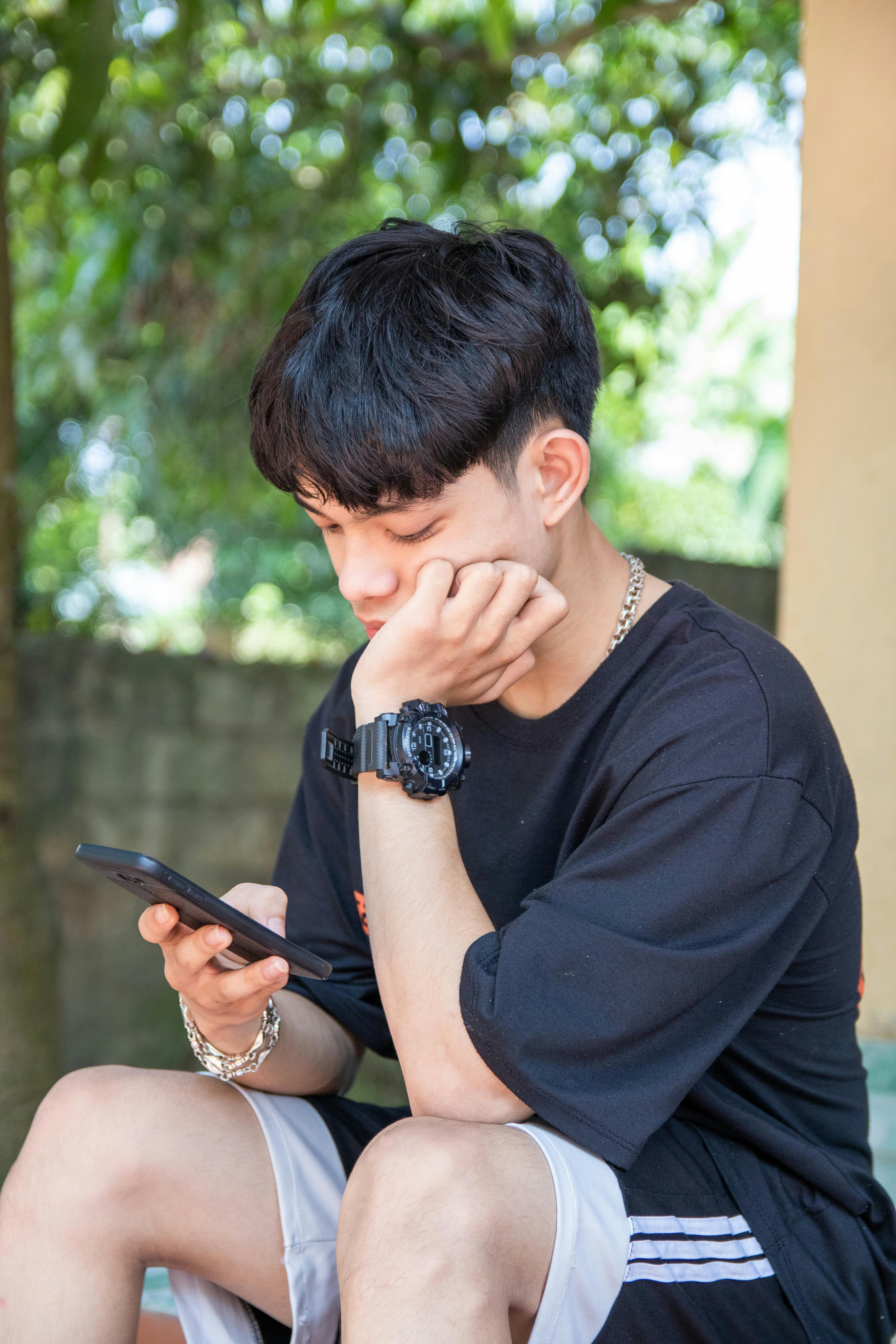 Bored teenage boy scrolling through his phone — the behavior at the center of the brain rot conversation