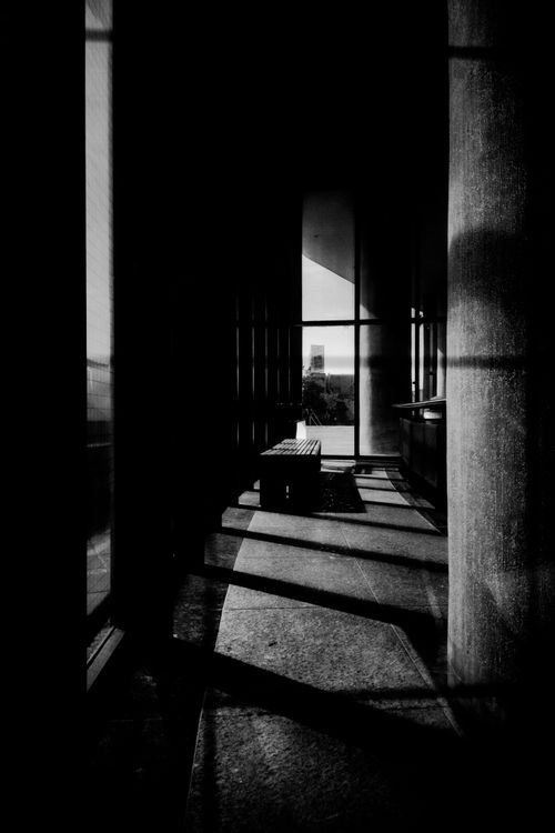 Free Black and white corridor with dramatic shadows and sunlight filtering through windows. Stock Photo