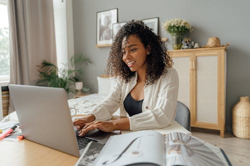 Free A Woman in White Long Sleeve Shirt Using a Laptop Stock Photo