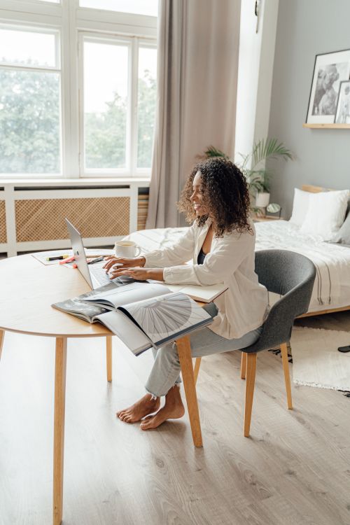 Free Woman working remotely on a laptop in a stylish home office, embracing a modern and comfortable work-from-home lifestyle. Stock Photo