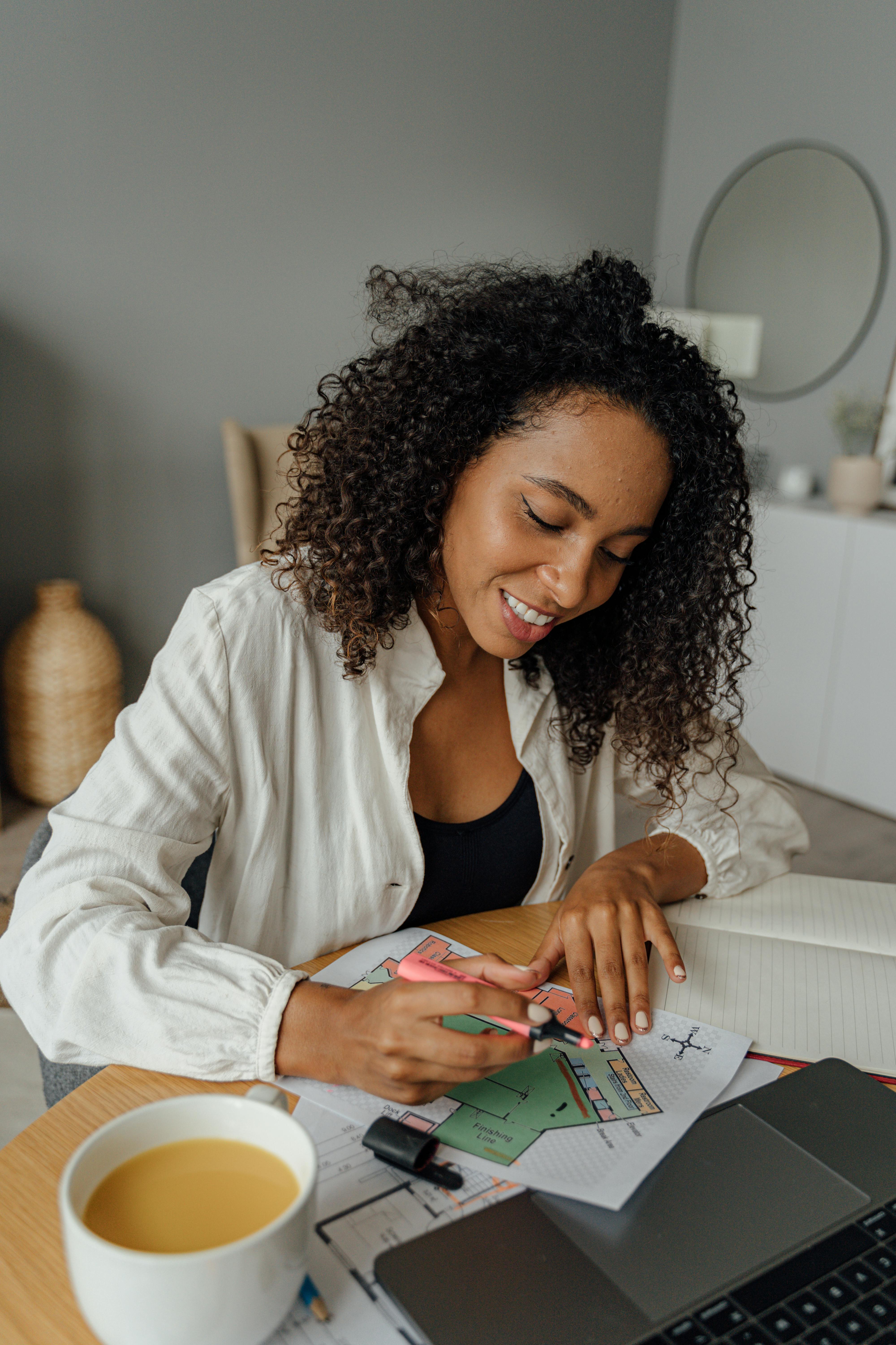 一位女士在家中面带微笑，用彩色笔和咖啡创造性地构思设计想法