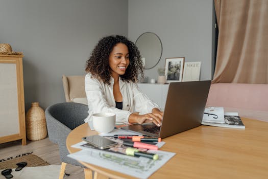 A happy woman working on a laptop in a cozy home office, enjoying freelance work.