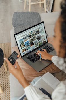 Woman using laptop and credit card for online shopping indoors, relaxed.