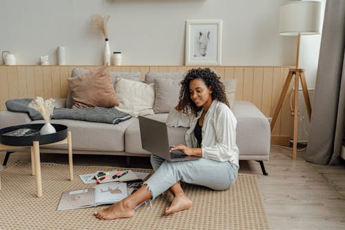 Free Woman in White Long Sleeve Using a Laptop while Sitting on the Floor Stock Photo