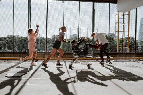 Free A group of friends enjoying a playful moment with a shopping cart in a bright parking deck. Stock Photo