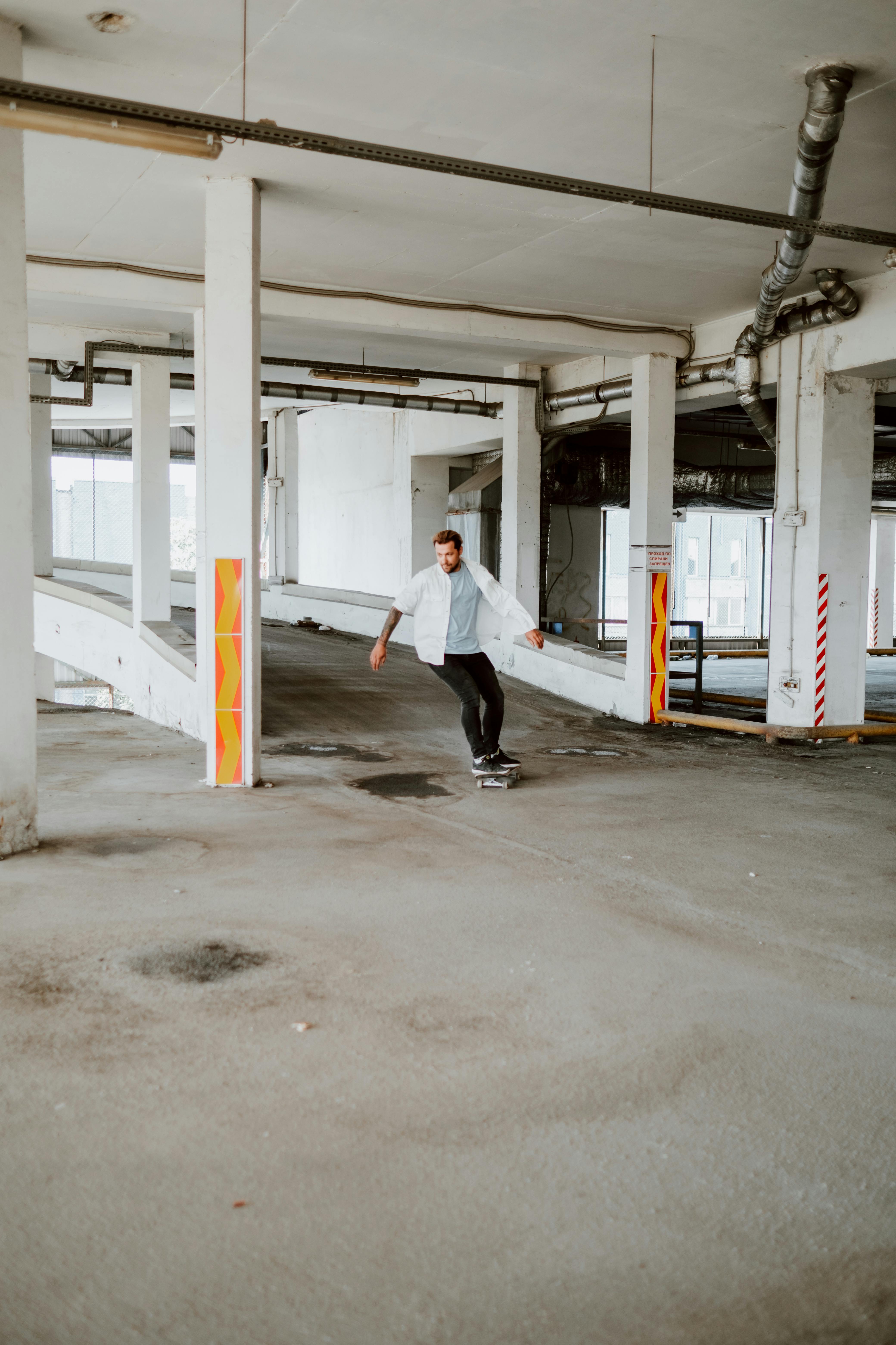 Free Skateboarder in an urban parking garage showcasing skills and style. Stock Photo