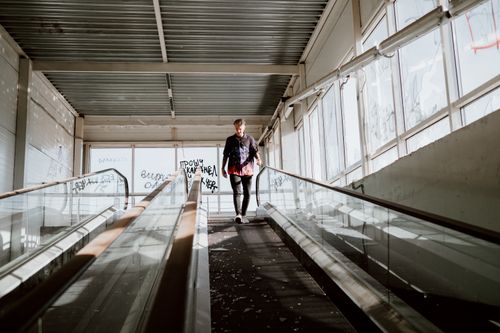 Free A man walks down an indoor escalator covered in graffiti, illuminated by natural light. Stock Photo