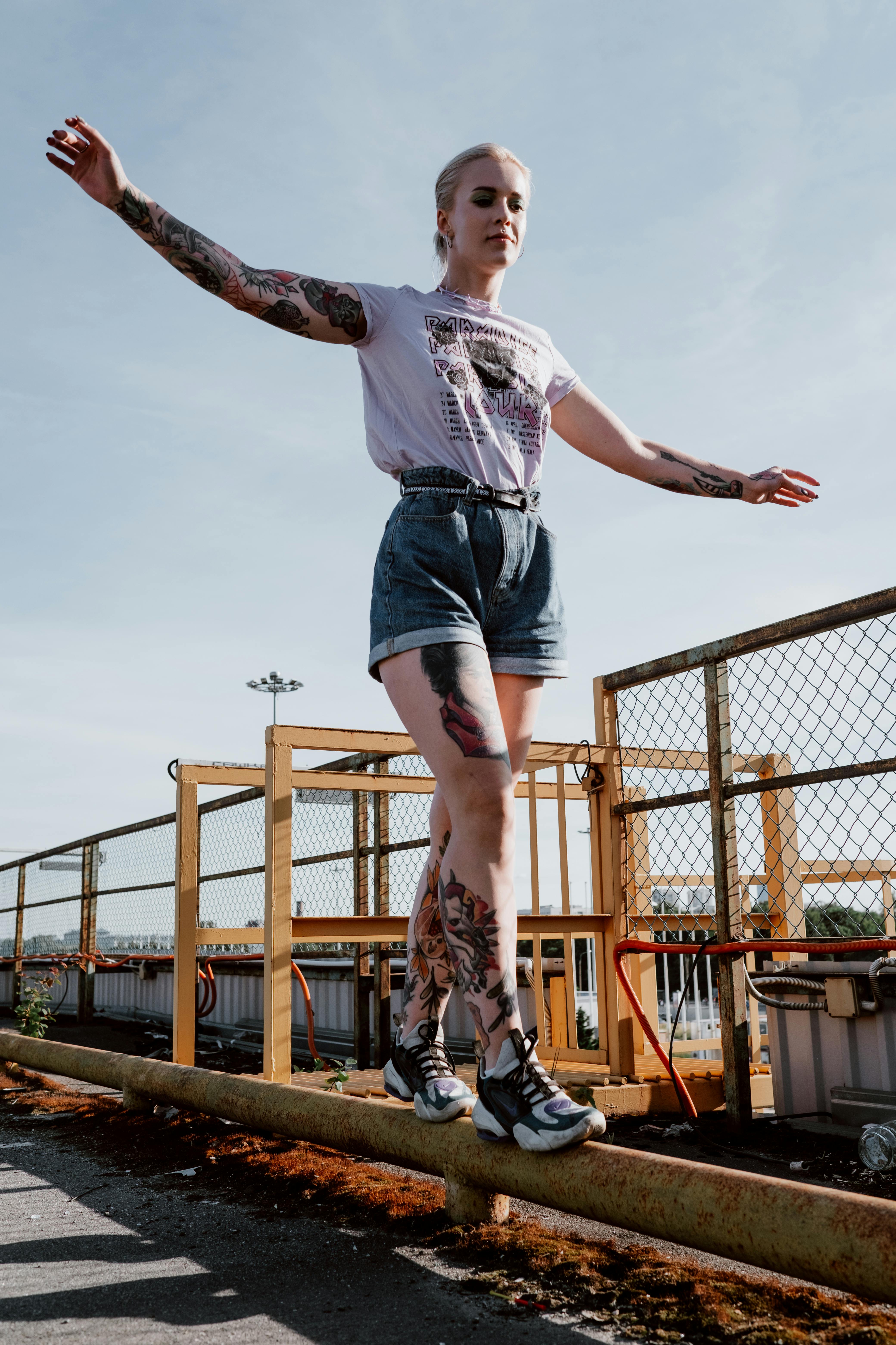 a woman in white top walking on a metal bar