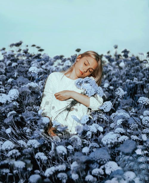 Serene female holding bunch of flowers in meadow