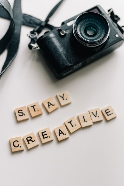 Creative photo of camera and tiles spelling 'Stay Creative' on white background.
