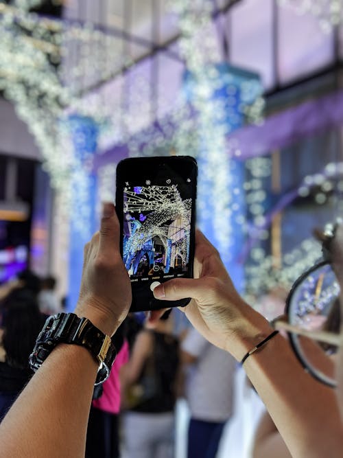 Person Taking Picture of Light Decorations on Cellphone 