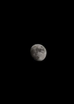 这张图像引人注目，深黑色的夜空中映衬着半轮月亮，展现出月球表面的陨石坑