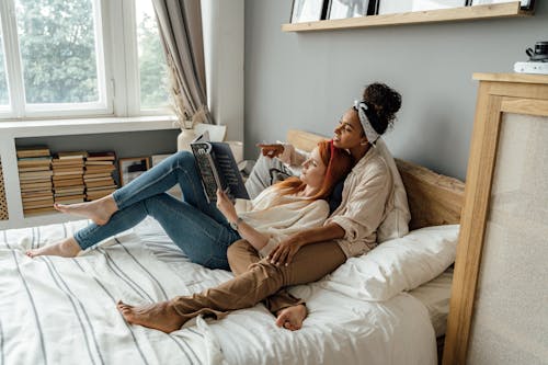 Free A Couple Lying on the Bed while Reading a Book Stock Photo