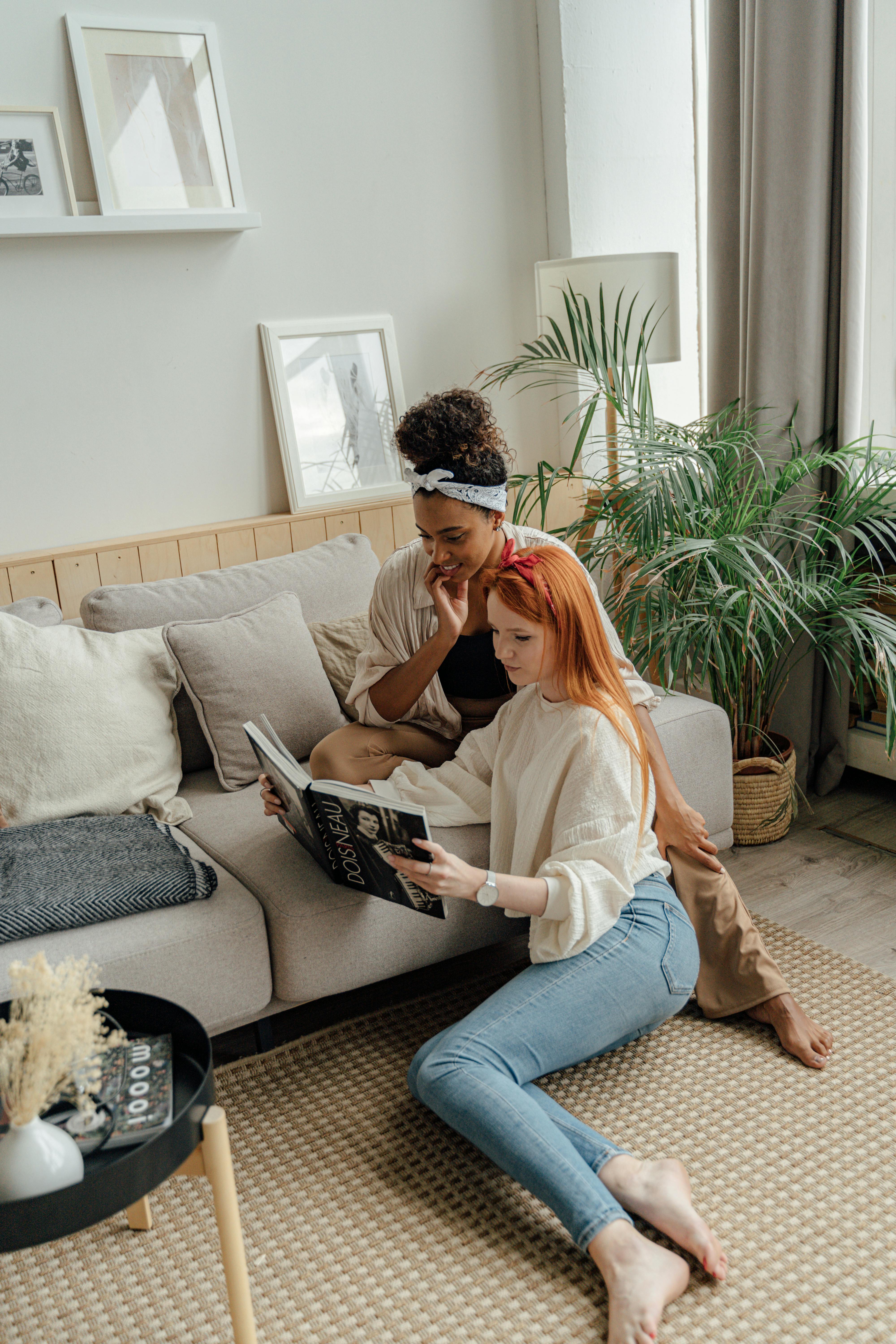 woman in white long sleeve shirt and blue denim jeans sitting on gray couch