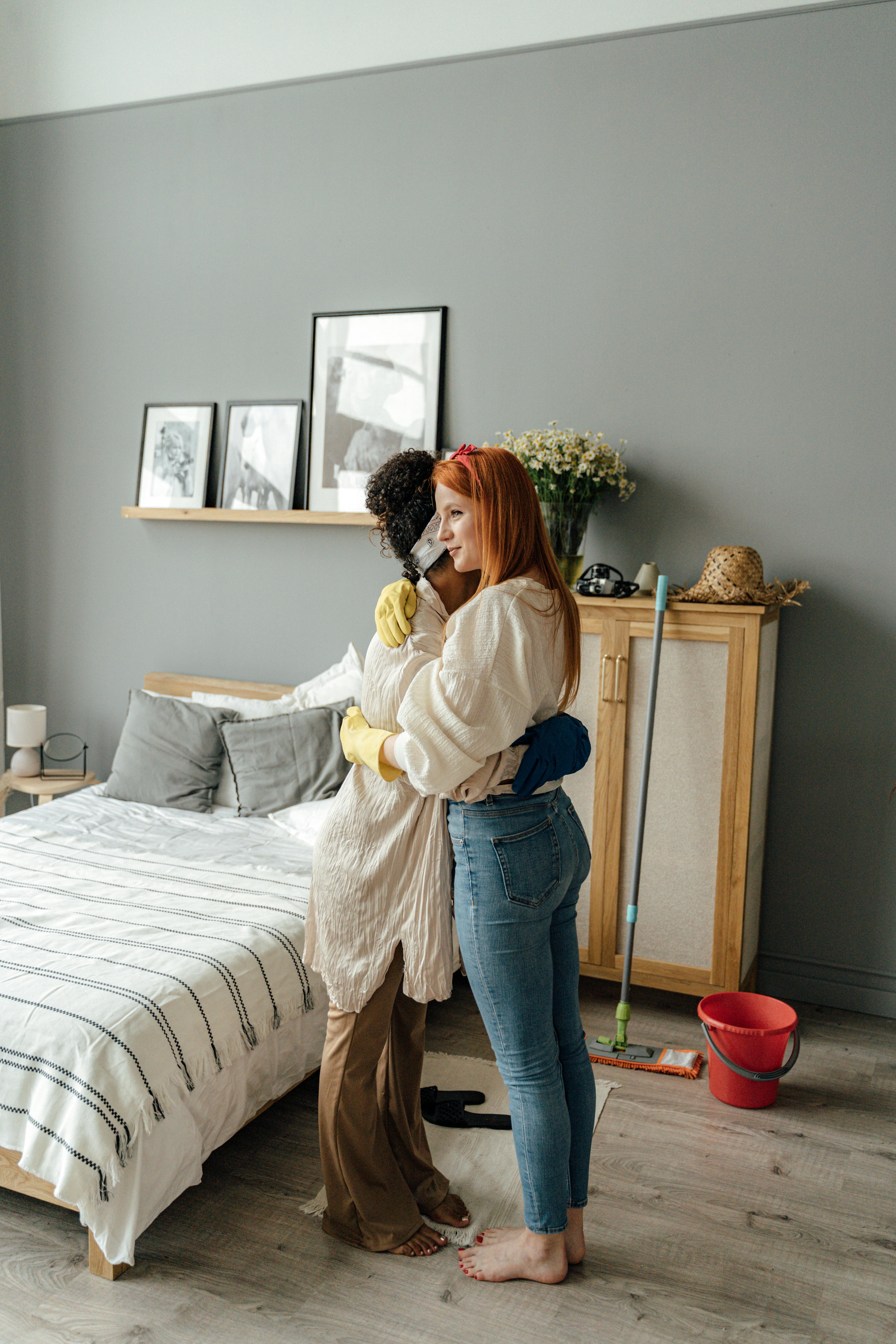 woman in white long sleeve shirt and blue denim jeans standing beside bed