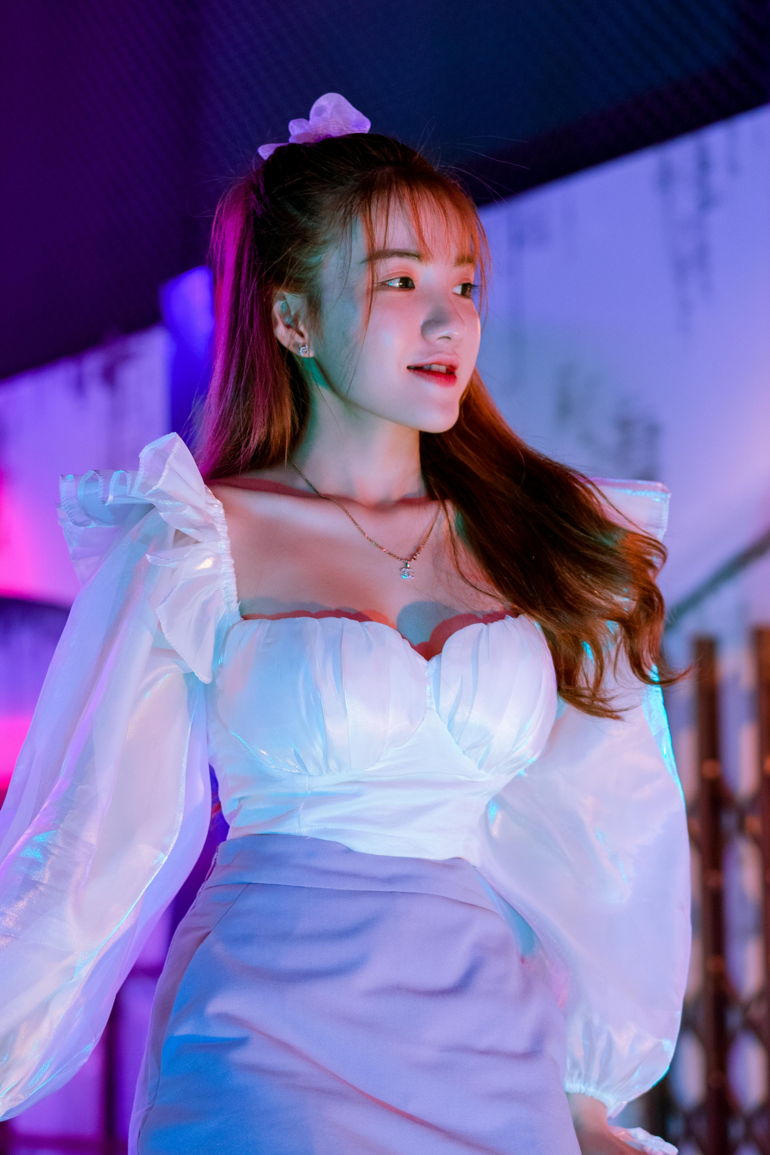 Smiling young ethnic lady chilling on illuminated city street at night