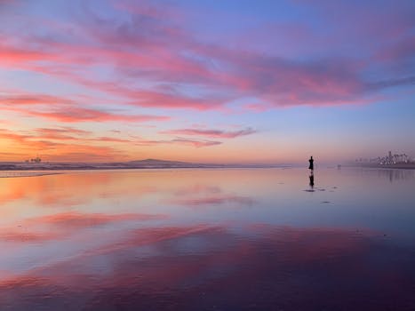 Beautiful sunset scene on Huntington Beach, CA, reflecting vibrant pink and blue skies on the ocean.
