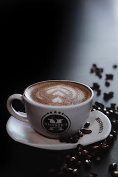 Close-up of a cup of cappuccino with latte art and coffee beans.