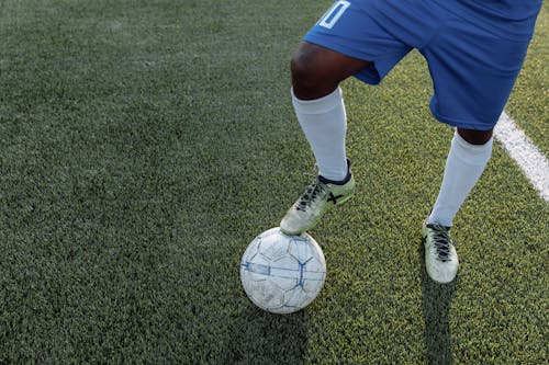 Free Person in Blue Shorts and White Socks Stepping on the Soccer Ball  Stock Photo