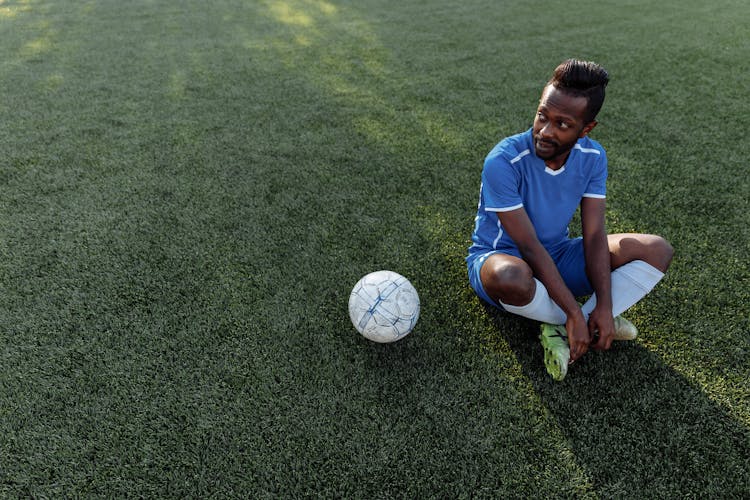 Football Player Sitting Beside A Ball 