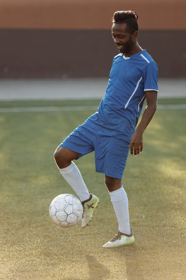 Man In Blue Soccer Jersey Kicking Soccer Ball