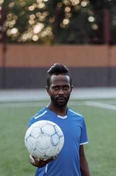 Portrait of a bearded African American man holding a soccer ball on an outdoor field.