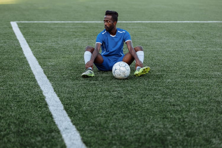 A Man Sitting On A Football Field