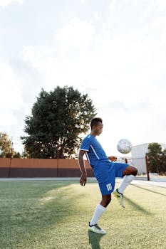 一名年轻运动员在阳光明媚的户外场地上练习足球技巧