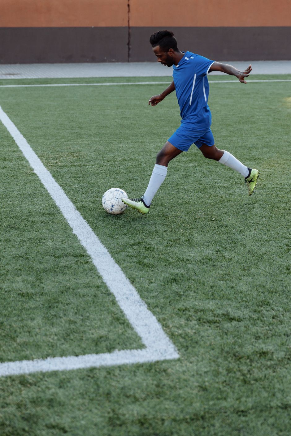 Footballer striking the ball on a green pitch