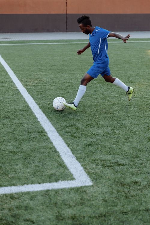 Free A young male soccer player kicks the ball on a green field, showing athletic skills. Stock Photo