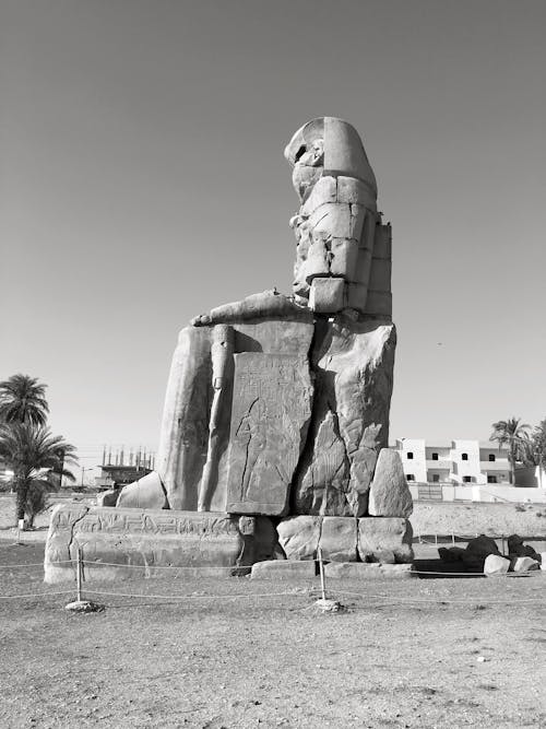 Low angle of black and white famous ancient Colossi of Memnon stone statue located Luxor on sunny day