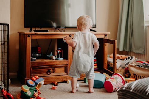 茶色の木製テーブルの横に立っている白いタンクトップと黒のショートパンツの少年